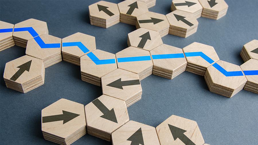 Wooden tiles with arrows form branching paths, with a blue line marking a clear route through them