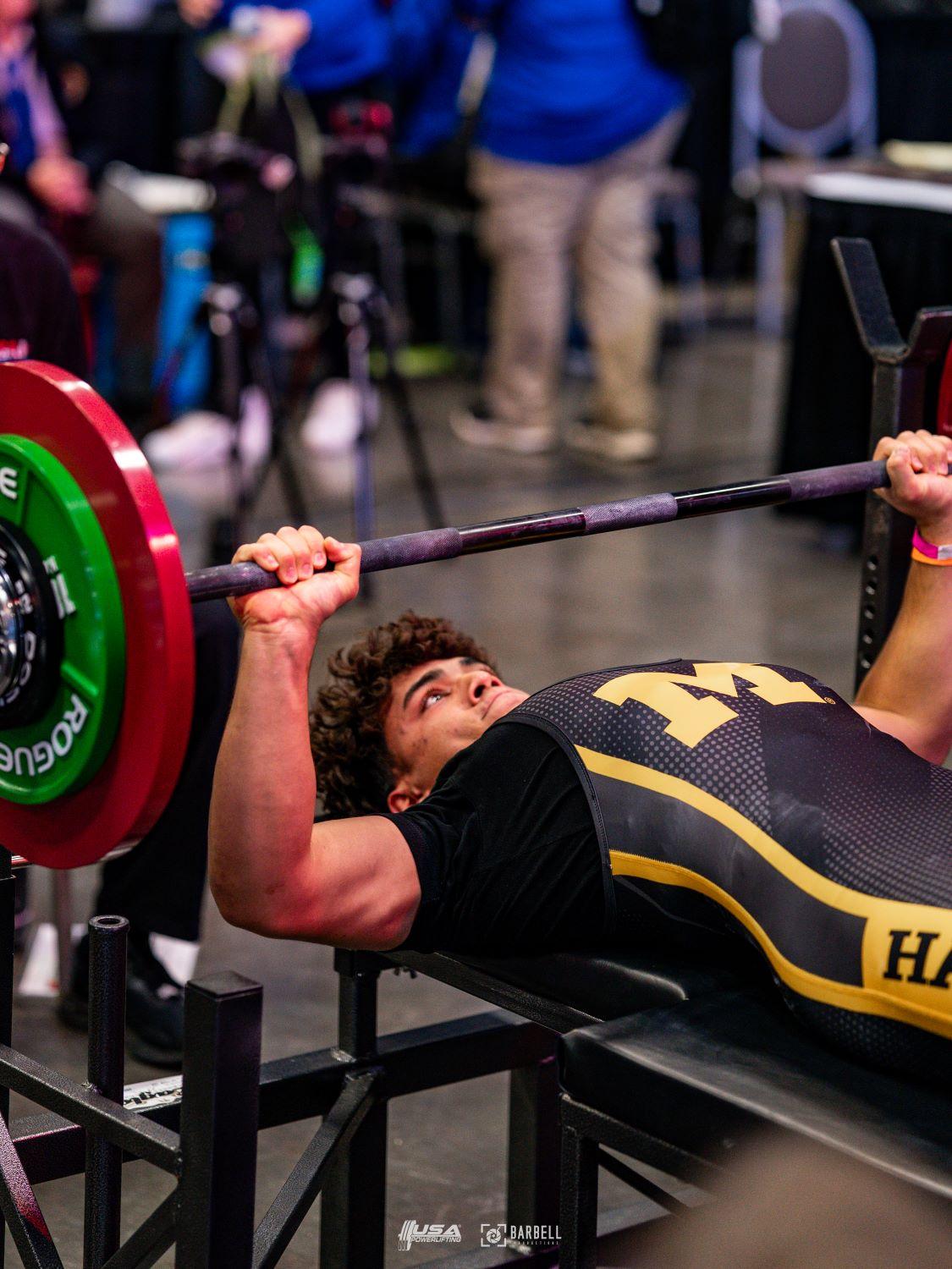 A close up shot of an athlete benching the bar with plates
