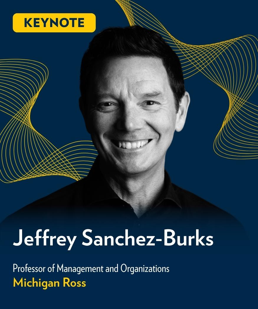 Keynote speaker Jeffrey Sanchez-Burks, Professor of Management and Organizations at Michigan Ross, smiles against a dark blue background with maize wave graphics.