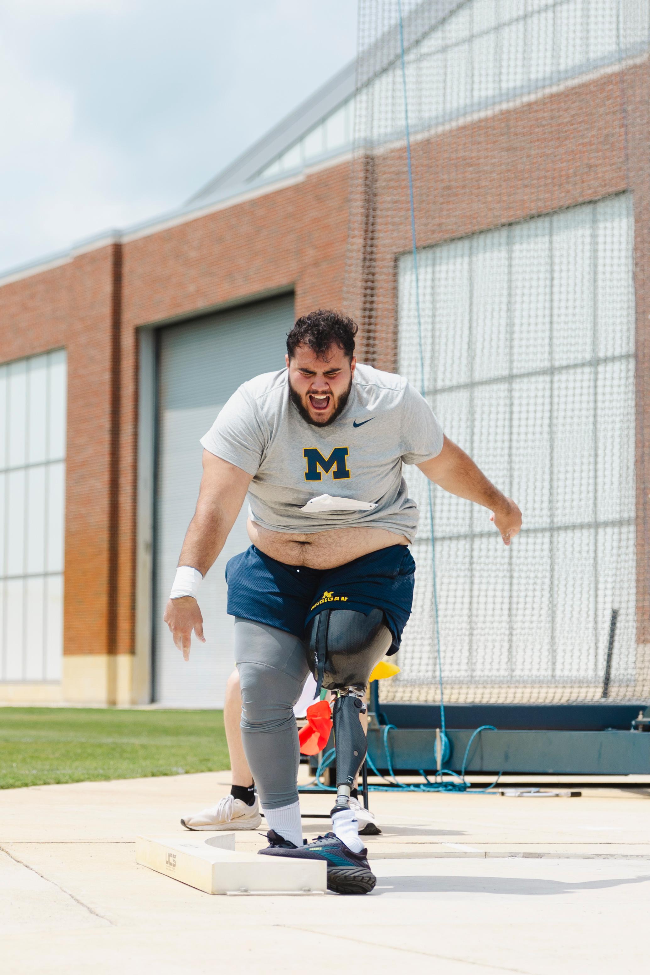 Adaptive athlete wearing a prosthetic leg mid-throw in the shot put competition